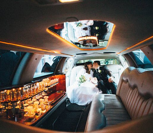 just married: Bride and groom kissing in a stretch limousine